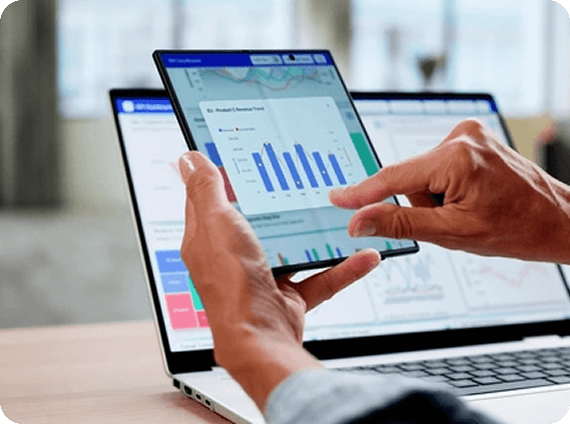 Person analyzing data on laptop and mobile device